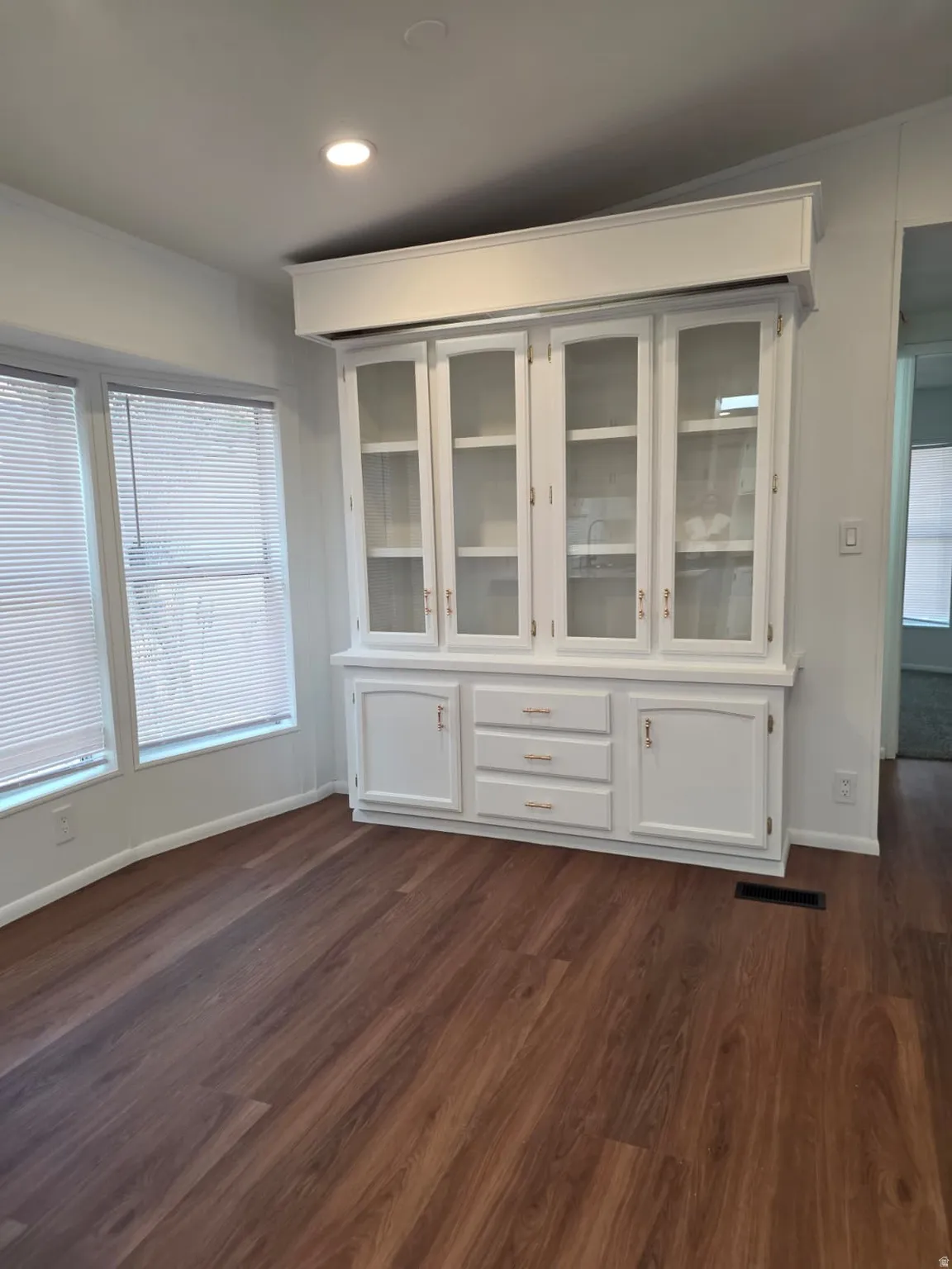 Built-in white cabinetry with glass display doors and brass hardware