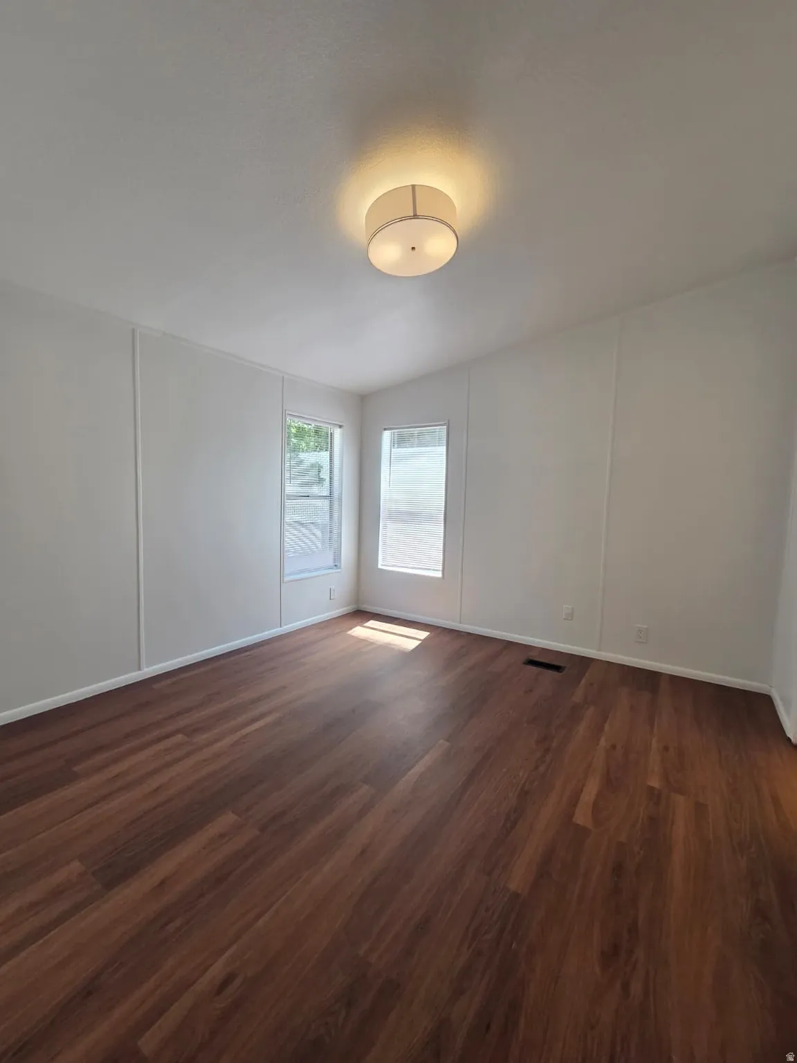 Spacious interior room white walls, multiple windows, and a flush-mount ceiling light fixture