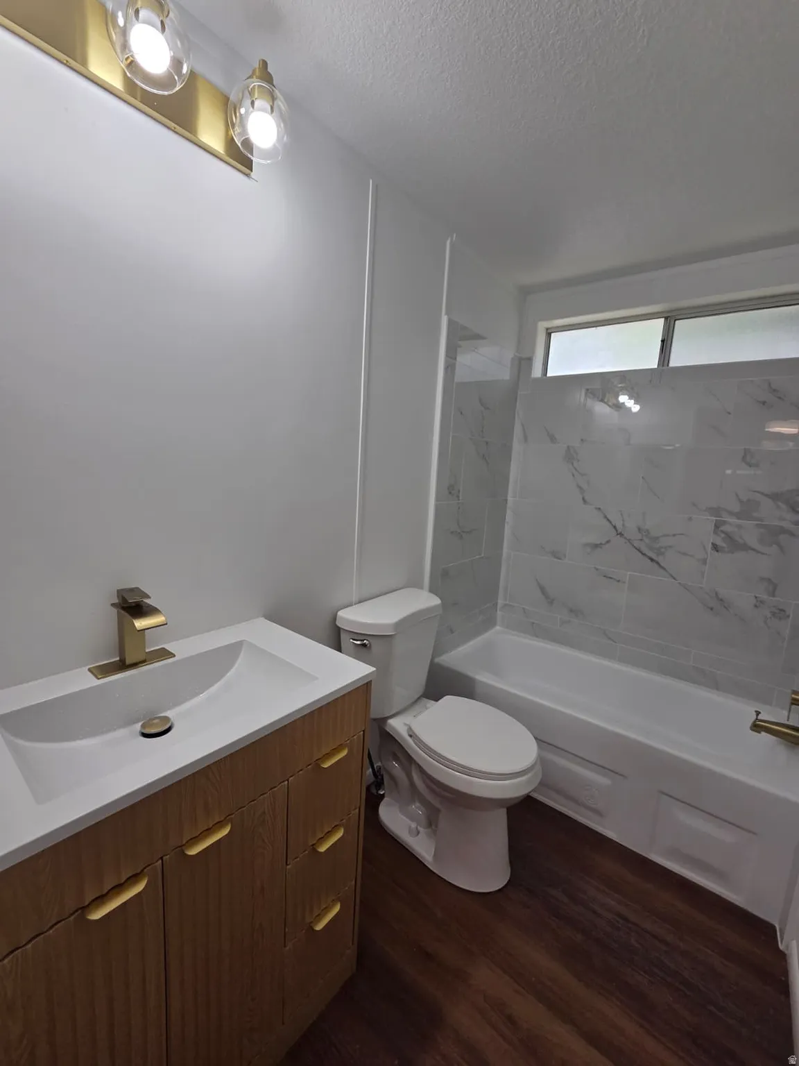 Bathroom featuring a vanity with a white integrated sink, gold-tone hardware, and a matching gold-tone faucet