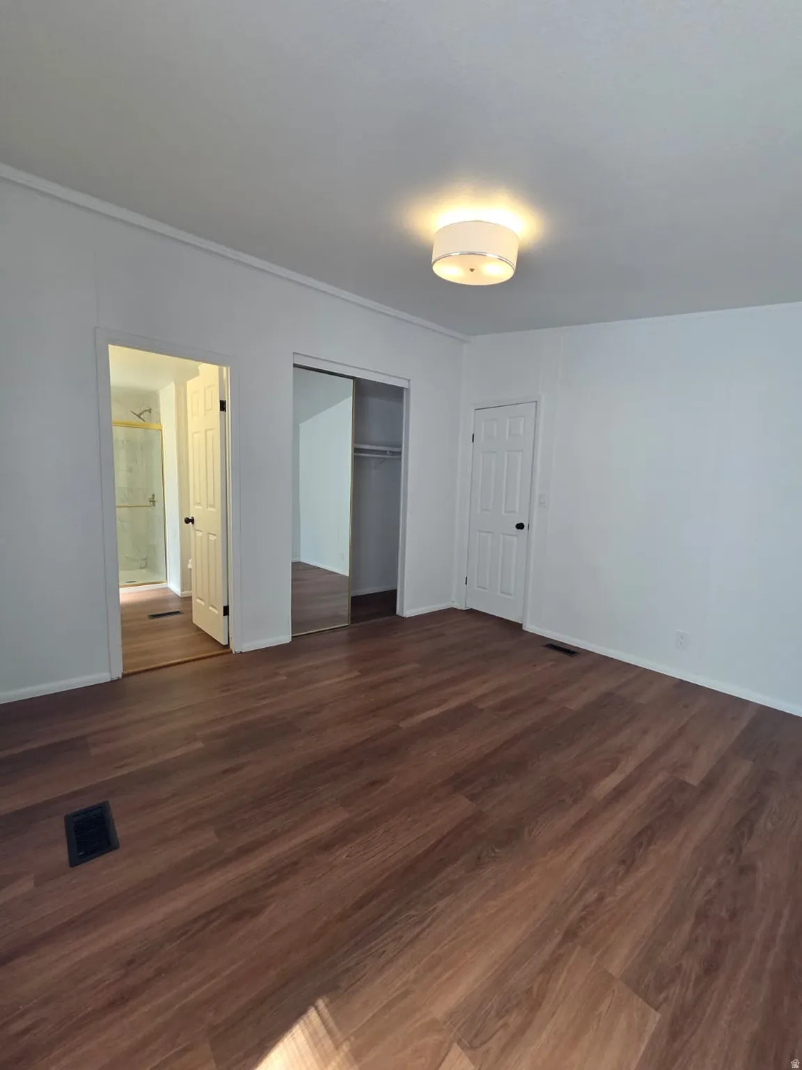 Spacious room featuring white walls, and a contemporary flush-mount ceiling light