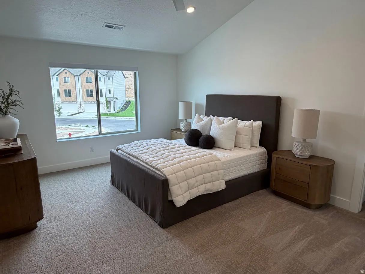 Carpeted room featuring a large window, vaulted ceiling, and recessed lighting