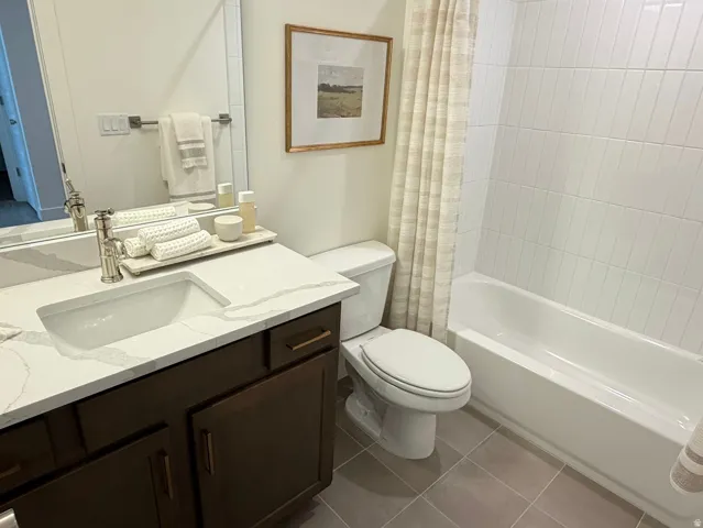 Bathroom featuring a vanity with a white countertop and integrated sink, dark wood-finish cabinetry, a built-in tub with white subway tile surround, and neutral floor tiling