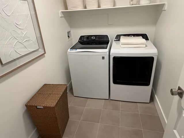 Utility room featuring a built-in shelf, neutral wall paint, and square floor tiles