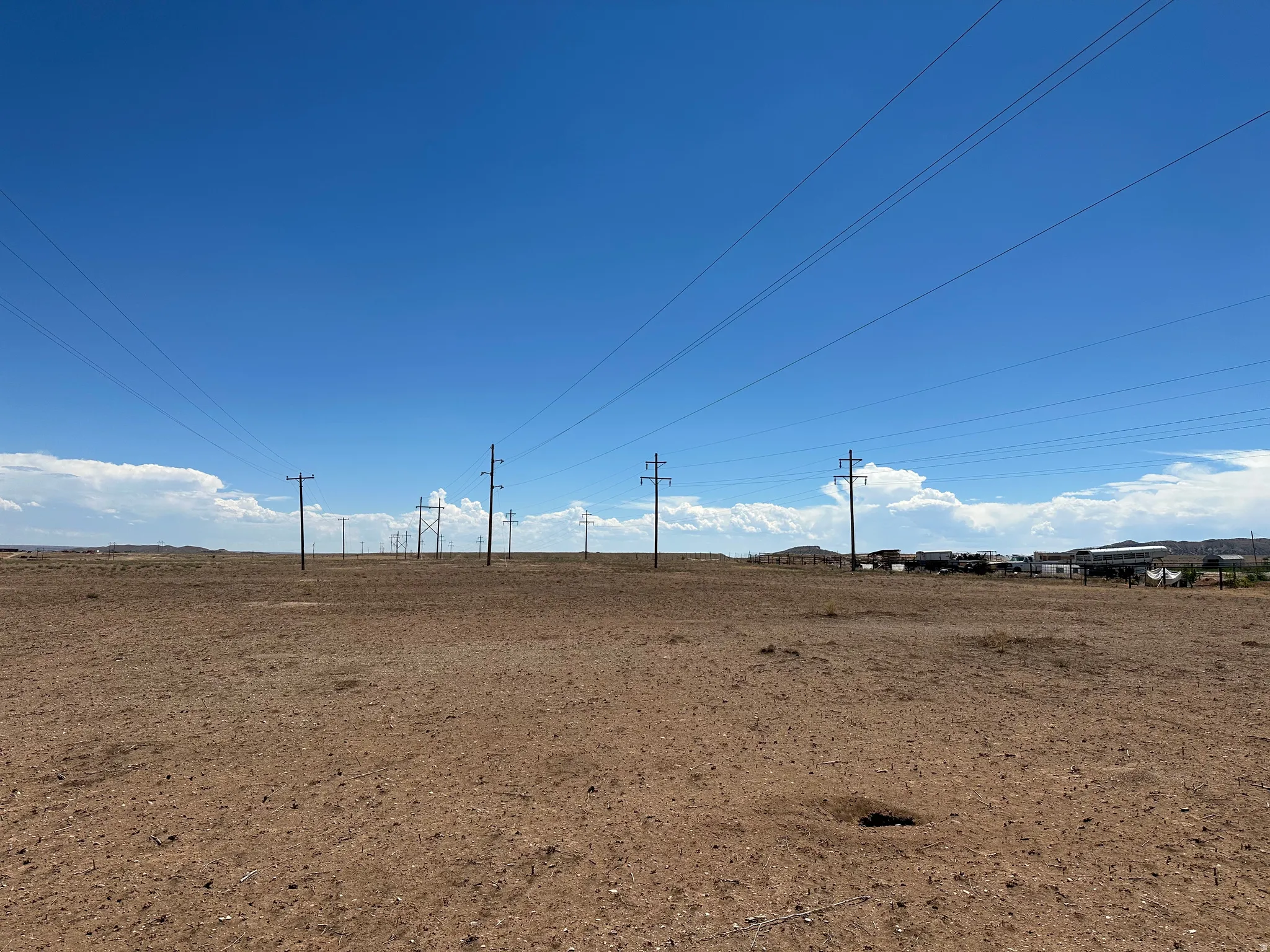 Expansive arid land parcel featuring a clear sky and distant structures