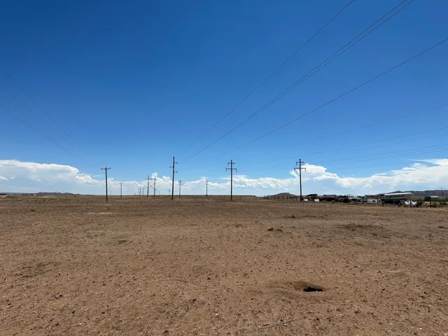 Expansive arid land parcel featuring a clear sky and distant structures