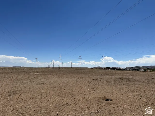 Expansive arid land parcel featuring a clear sky and distant structures