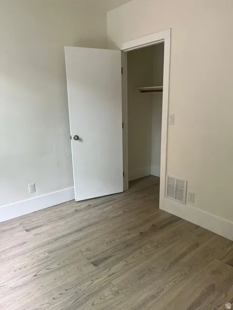 Room featuring wood-finish flooring, white baseboards, and a neutral wall palette