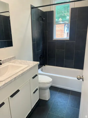 Bathroom featuring a white vanity with a light-toned countertop, an integrated sink, and matte black hardware