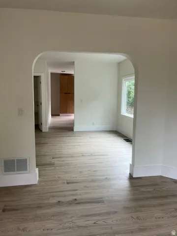 Expansive arched doorway with wood-finish flooring, crisp white baseboards, and neutral wall tones