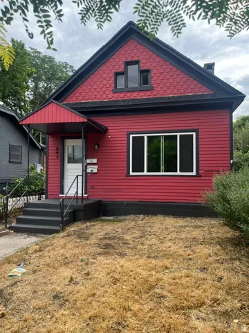 Red siding exterior with black trim, a gabled roofline, and a prominent front entrance