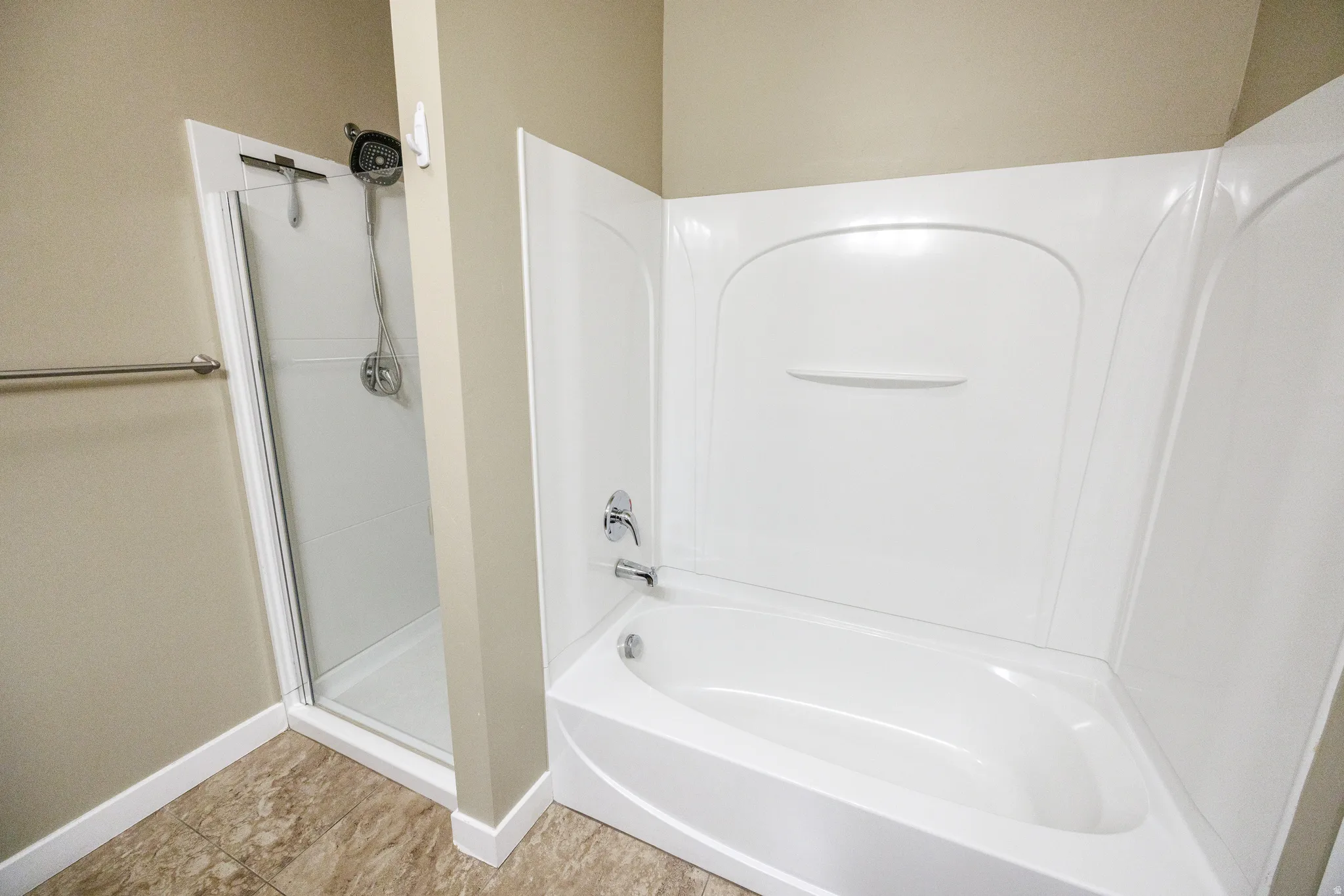 Bathroom featuring a full-size bathtub with integrated shower surround, separate glass-enclosed shower stall, chrome fixtures, and neutral-toned wall paint