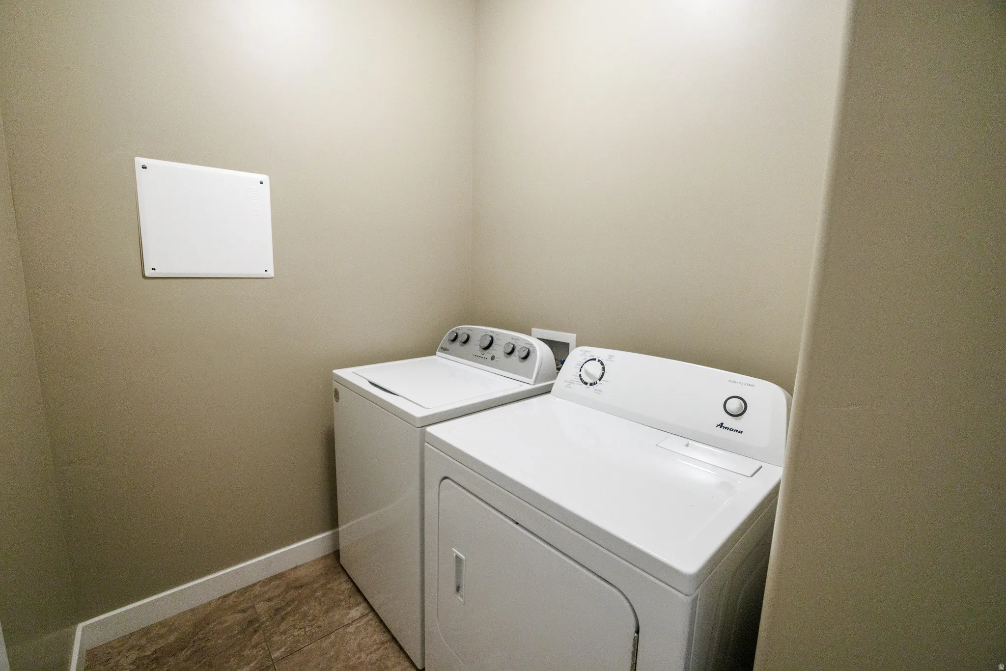 Utility area with neutral wall paint, white baseboards, and wood-finish flooring