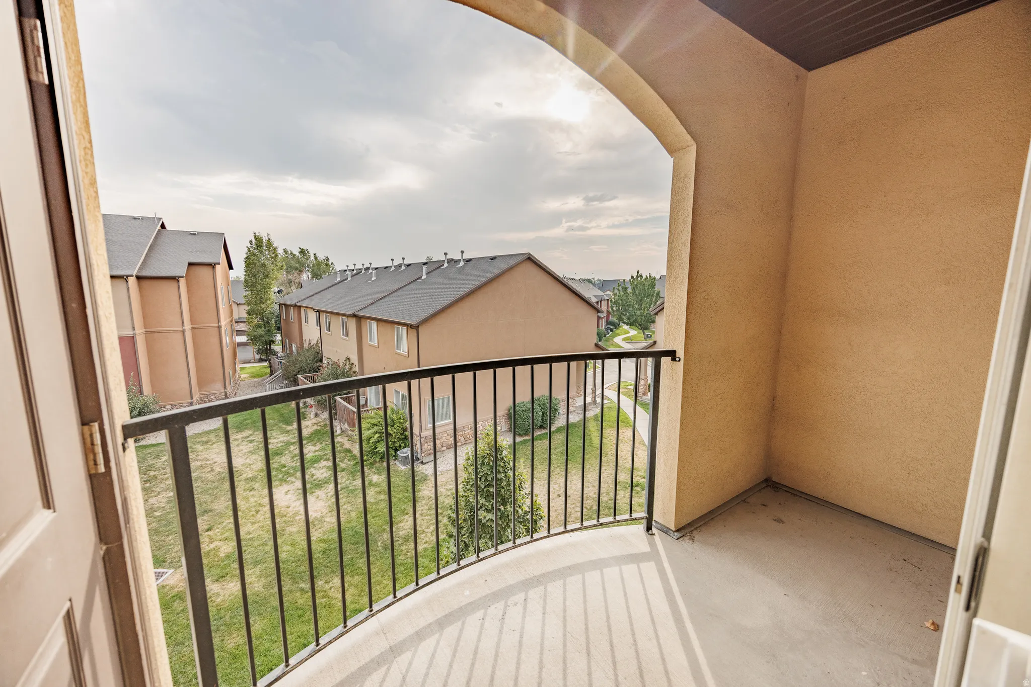 Private balcony with a curved metal railing and stucco exterior
