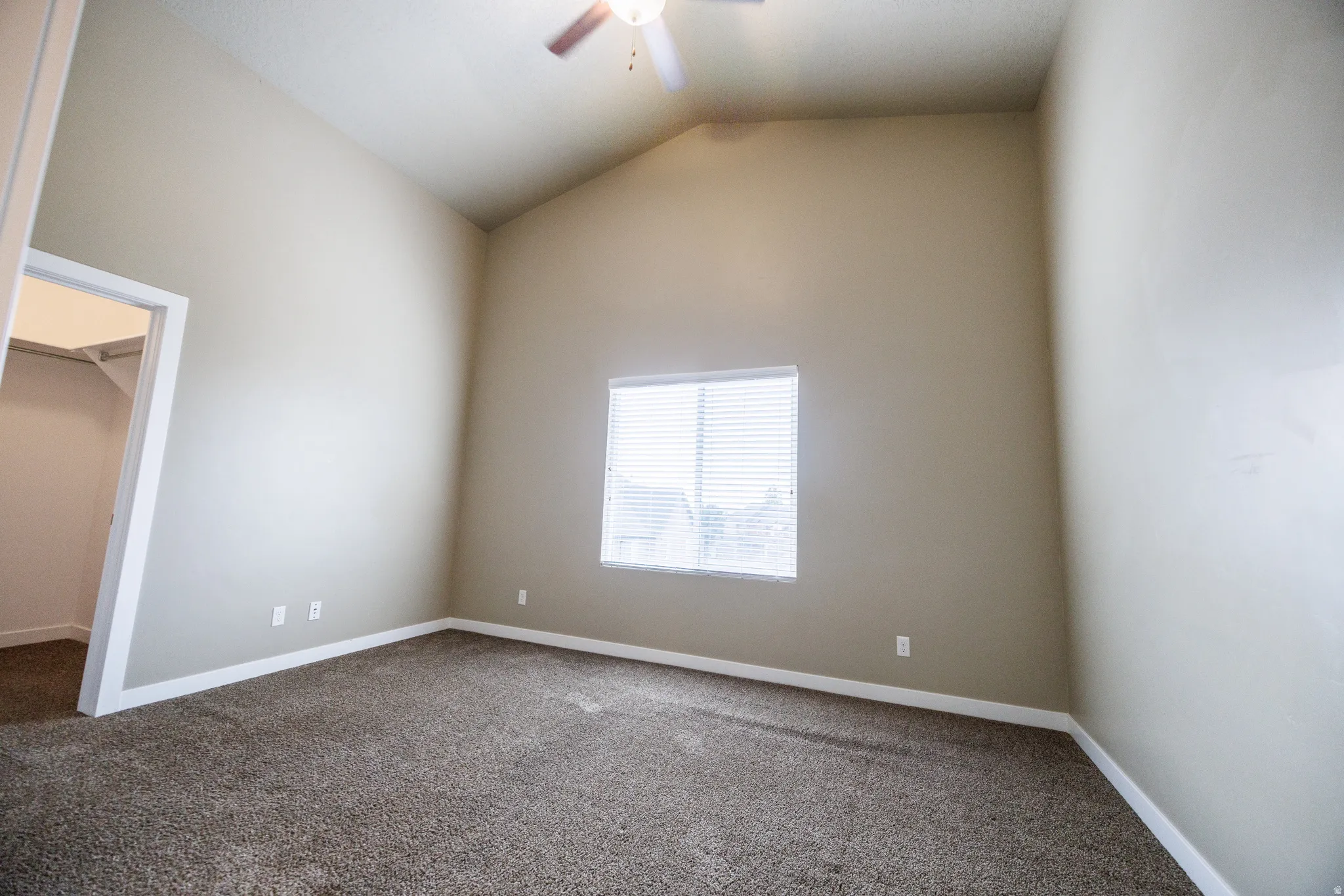 Carpeted room featuring a vaulted ceiling and a ceiling fan