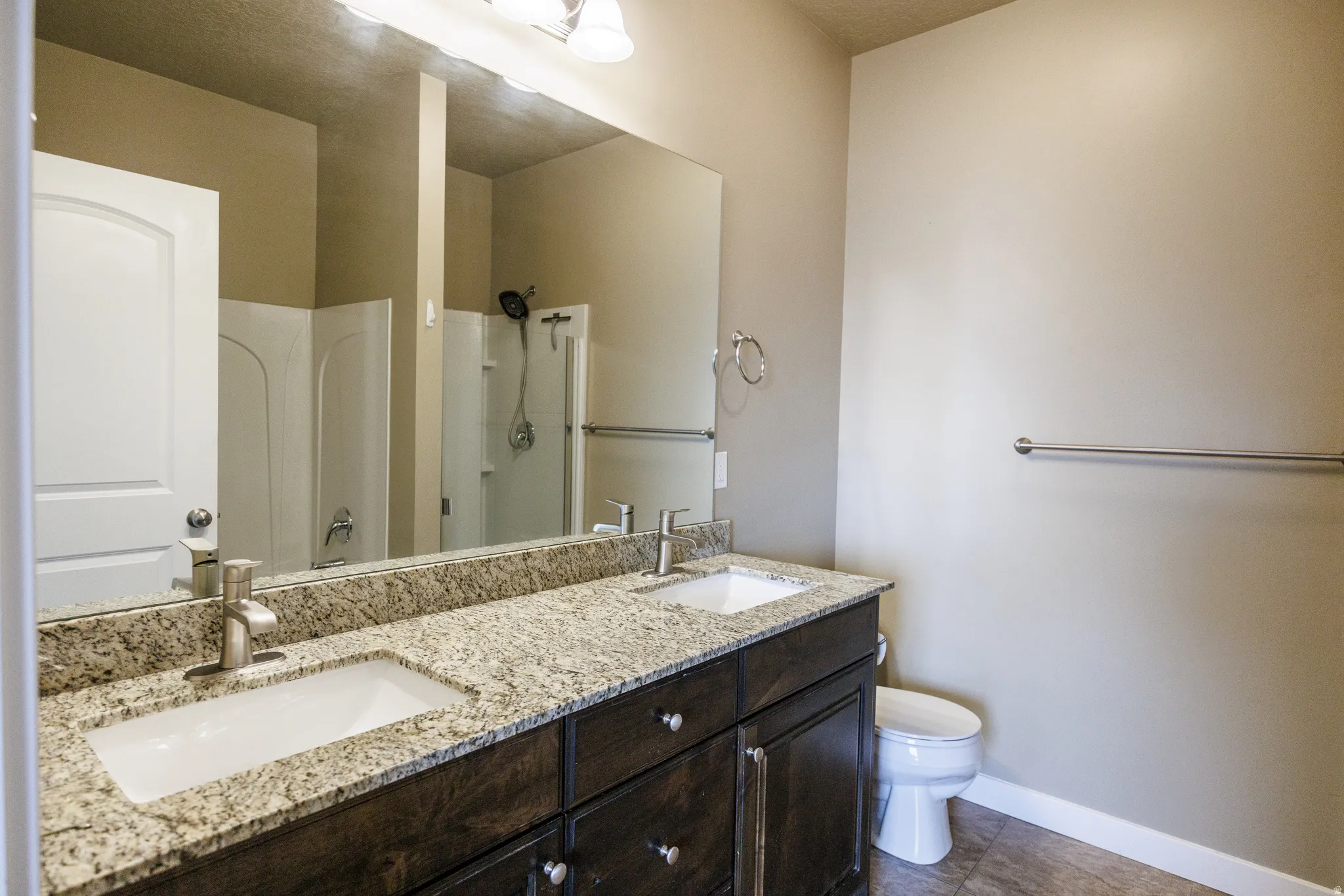 Bathroom featuring a dual vanity with a speckled countertop, undermount sinks, and brushed nickel faucets