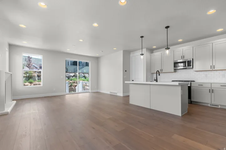 Spacious room featuring wood-finish flooring, recessed lighting, and a kitchen area