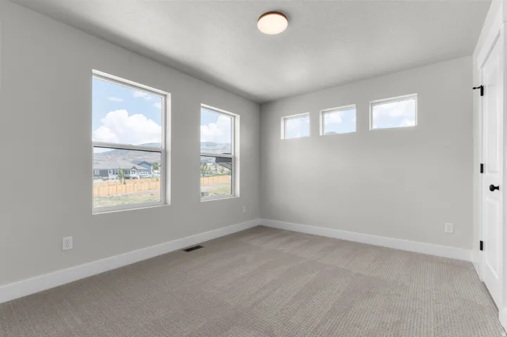 Neutral-toned room featuring light gray walls, plush carpeting, and white baseboards