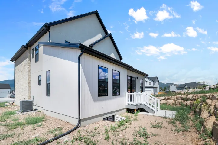 Contemporary exterior with mixed material facade, featuring white vertical siding and light-colored stone accents