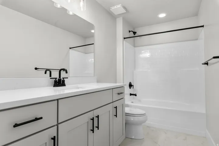 Bathroom featuring a light-toned vanity with black hardware, white countertop, and integrated sink