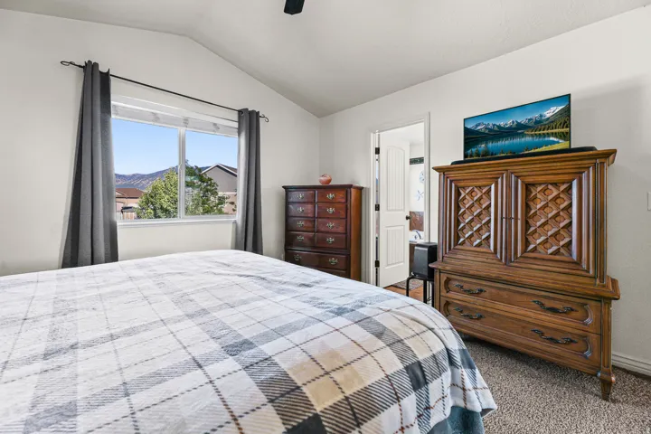 Vaulted ceiling bedroom with a large window offering mountain scenery