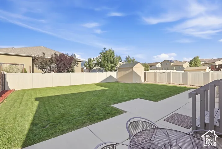 Expansive backyard with a manicured lawn, full privacy fencing, and a dedicated storage shed