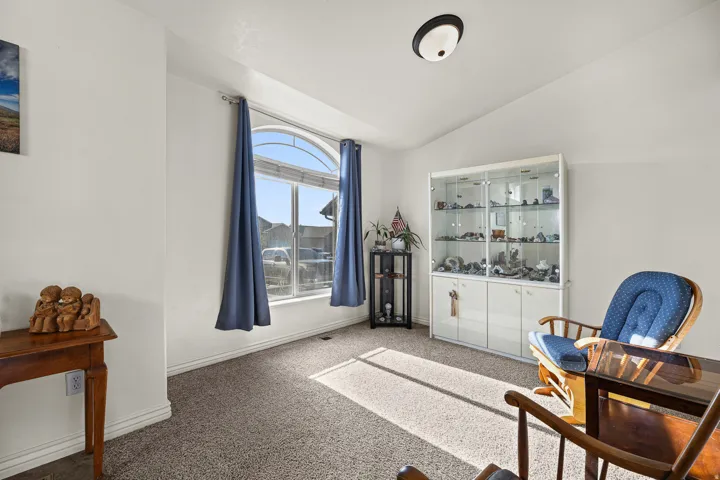 Vaulted ceiling with an arched window, white walls, and neutral carpet flooring