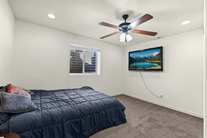 Carpeted room featuring a ceiling fan with integrated lighting, recessed ceiling lights, and a window with blinds