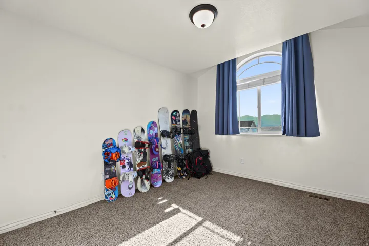 Arch-top window with blue curtains, light grey wall paint, and neutral carpet flooring