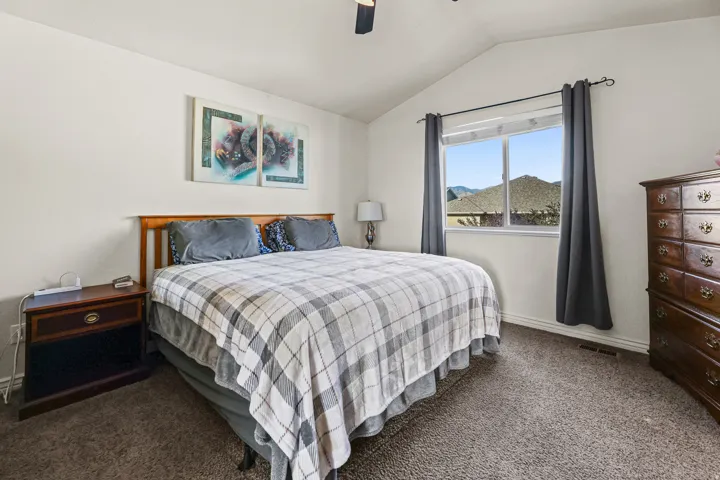 Carpeted bedroom featuring a vaulted ceiling and a wood-frame window with mountain scenery