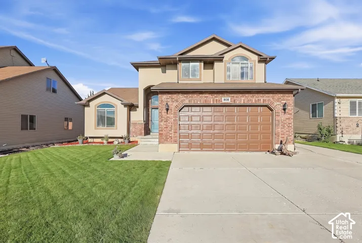 Two-story residence featuring a brick and stucco facade, an arched entry, and a two-car attached garage