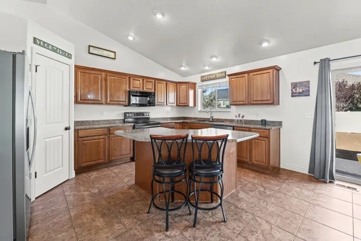 Kitchen featuring an L-shaped island with a breakfast bar, recessed lighting, wood cabinetry, built-in microwave, and a sliding glass door