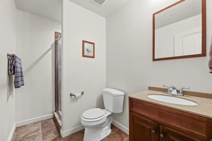 Bathroom featuring a glass-enclosed shower, a vanity with a light-toned countertop, and a framed mirror