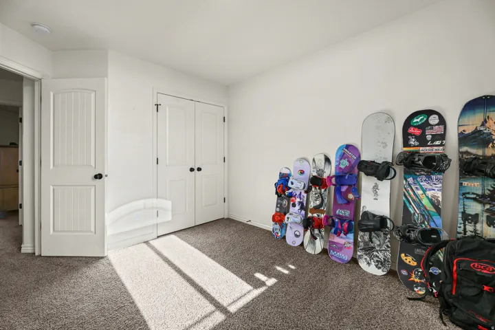 Carpeted room featuring white walls and a built-in closet with double doors and black hardware