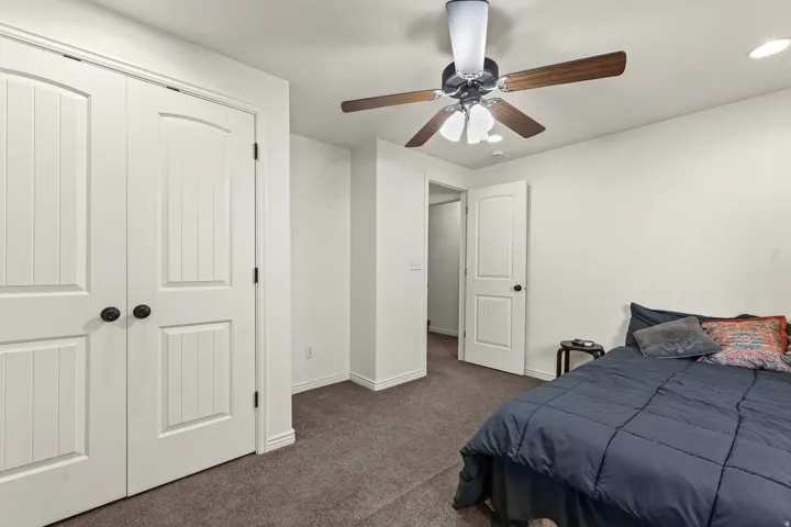 Bedroom featuring carpet flooring, crisp white walls, a ceiling fan with integrated lighting, and a solid core door