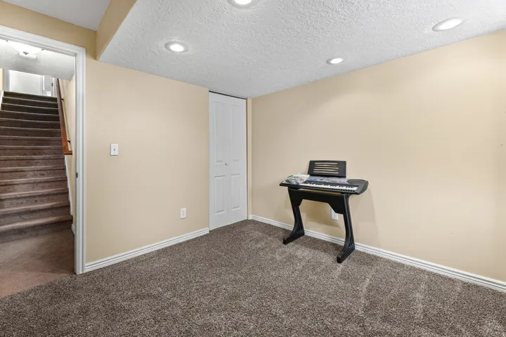 Carpeted room featuring recessed lighting, neutral wall paint, white baseboards, and a bi-fold closet door