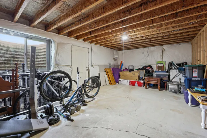 Unfinished basement offering exposed ceiling joists, concrete flooring, framed wall sections, and a window well