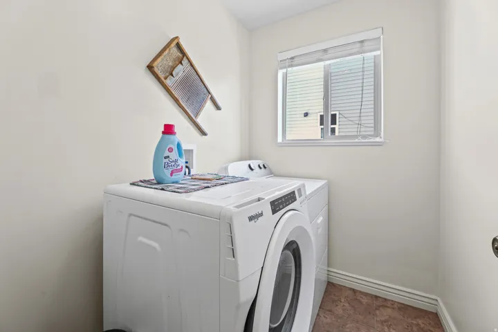 Dedicated laundry area featuring a window, light-toned walls, baseboard molding, and patterned flooring