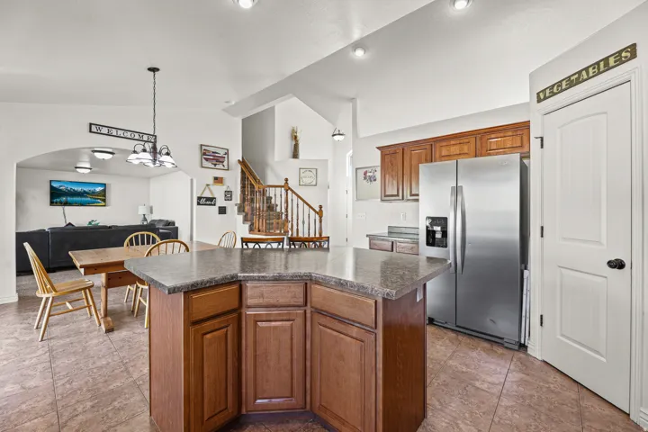 Kitchen featuring a central island with stone-finish countertop, wood cabinetry, and stainless steel refrigerator