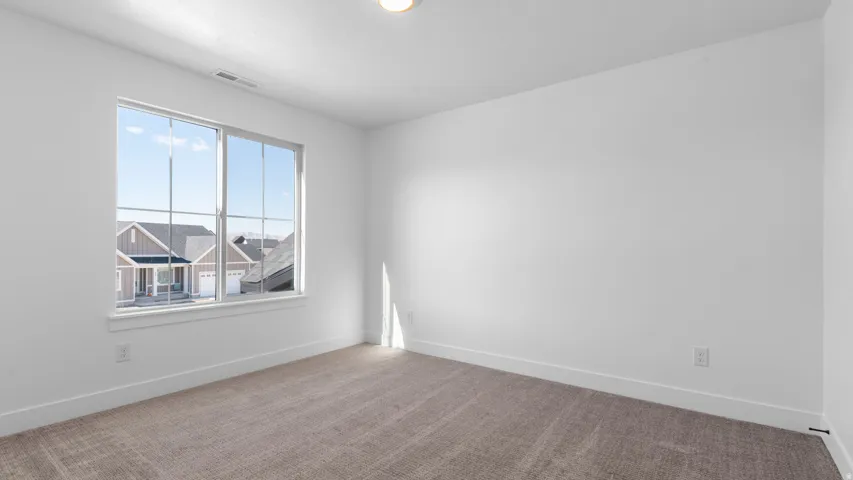 Room featuring a large window with white trim, neutral carpet, white walls, and a ceiling-mounted light fixture