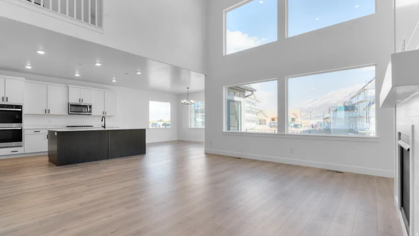Expansive open-concept living space featuring a modern kitchen, double-height ceilings, and abundant natural light from large windows