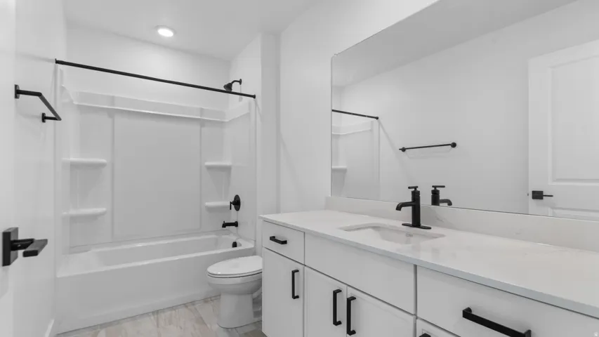 Modern bathroom featuring a double vanity with an integrated sink, quartz countertop, matte black fixtures, and wood-finish flooring