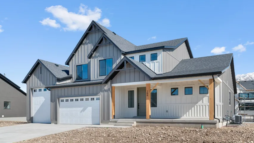 Modern farmhouse exterior featuring board and batten siding, a covered front porch with exposed wood beams, and a two-car garage