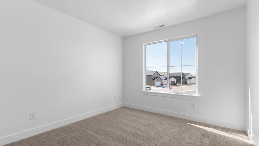 Bright room featuring white walls, white trim, light-colored carpet flooring, and a large window with grid panes