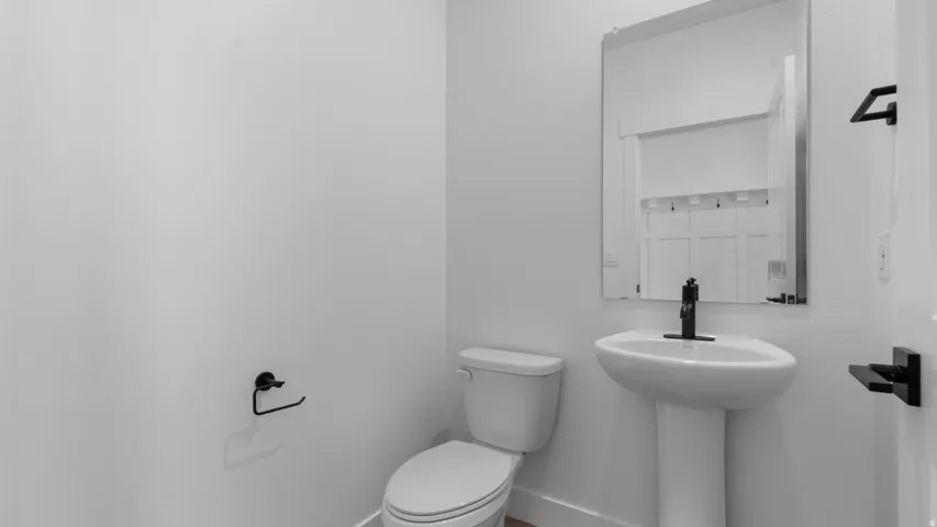 Pedestal sink with a black single-handle faucet, rectangular wall mirror, and modern black hardware