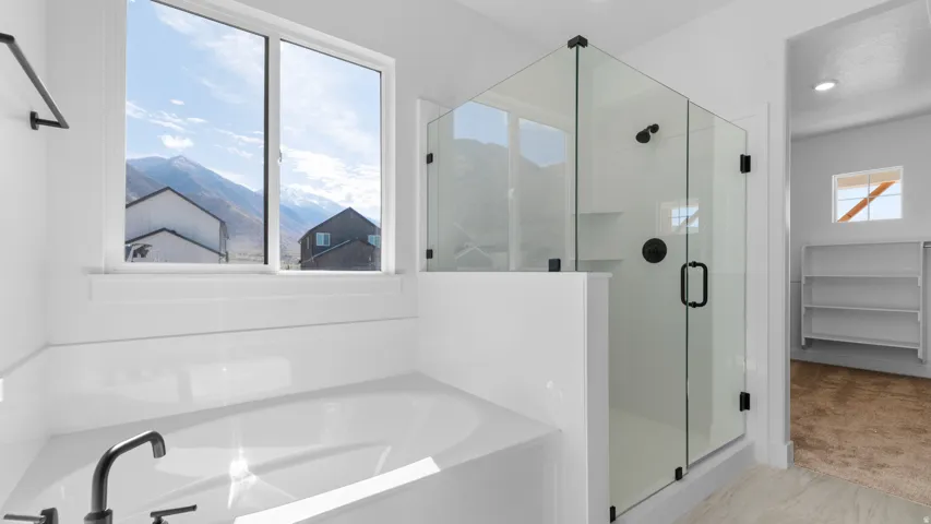 Freestanding soaking tub with matte black fixtures, alongside a glass-enclosed shower with matte black hardware