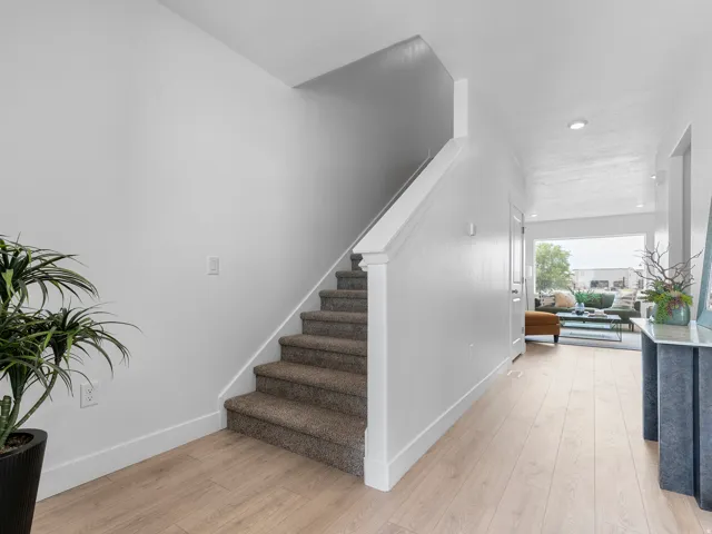 Entryway featuring light wood-finish flooring, white baseboards, and a carpeted staircase with white banister