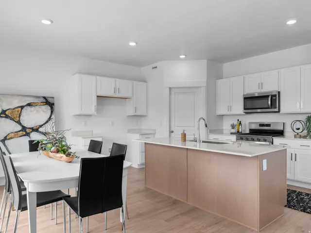 Kitchen and dining area featuring a light wood-finish island with a white countertop and integrated sink