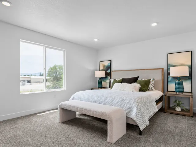 Bright bedroom featuring a large window, recessed lighting, neutral-toned walls, and plush carpeting