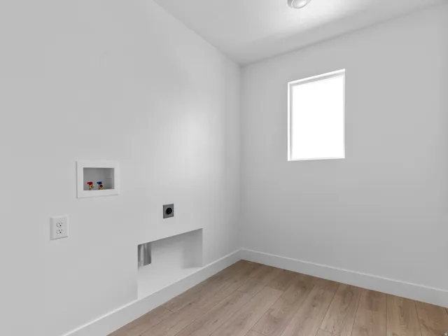 Dedicated laundry space featuring wood-finish flooring, a bright window, and essential hookups for appliances