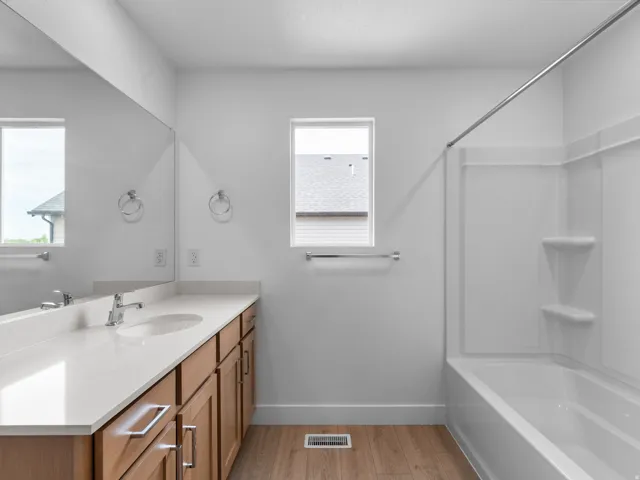 Bathroom featuring a double vanity with stone countertops, wood-finish cabinetry, and an integrated tub and shower unit